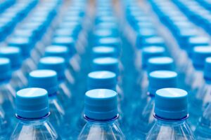 Array of blue plastic water bottles with caps arranged in a pattern. Ideal for recycling and packaging themes.
